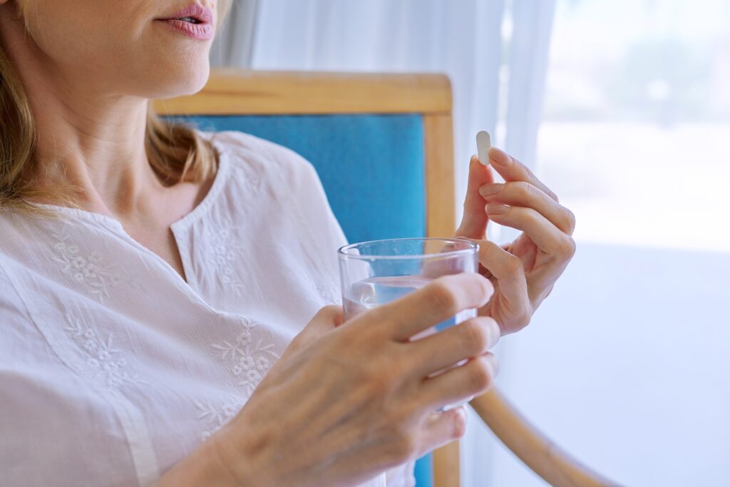middle aged woman taking pill at home in chair 2023 11 27 05 04 56 utc