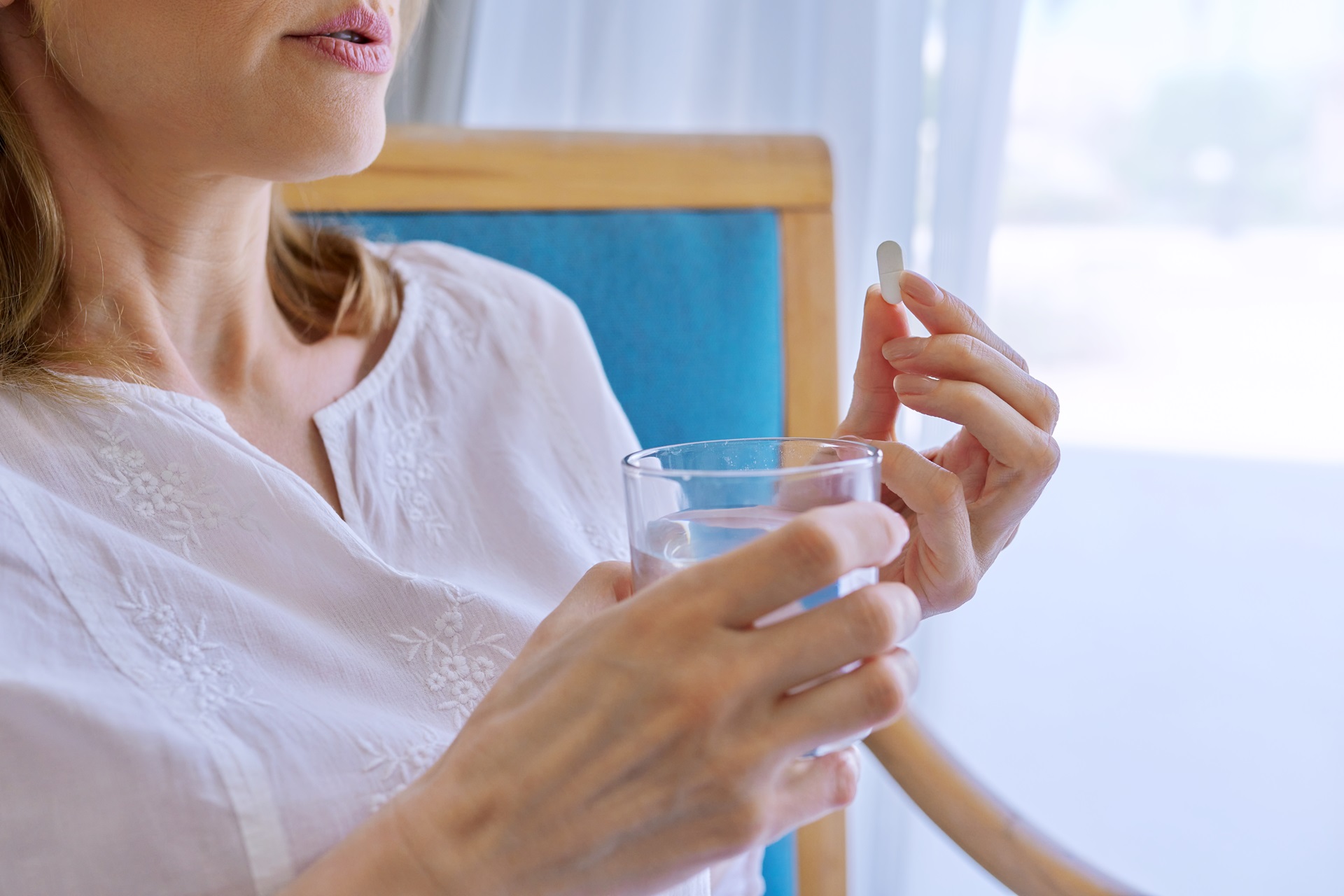 middle aged woman taking pill at home in chair 2023 11 27 05 04 56 utc